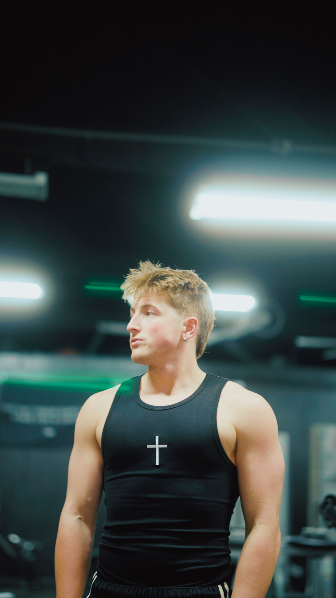 Saint Kaizen Cross Stringer - Black. Christian gym wear tank top with a bold cross symbol design. Deep-cut, performance fit for maximum range of motion during lifts.