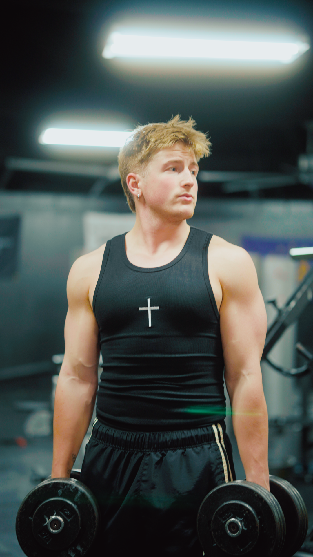 Saint Kaizen Cross Stringer - Black. Christian gym wear tank top with a bold cross symbol design. Deep-cut, performance fit for maximum range of motion during lifts.