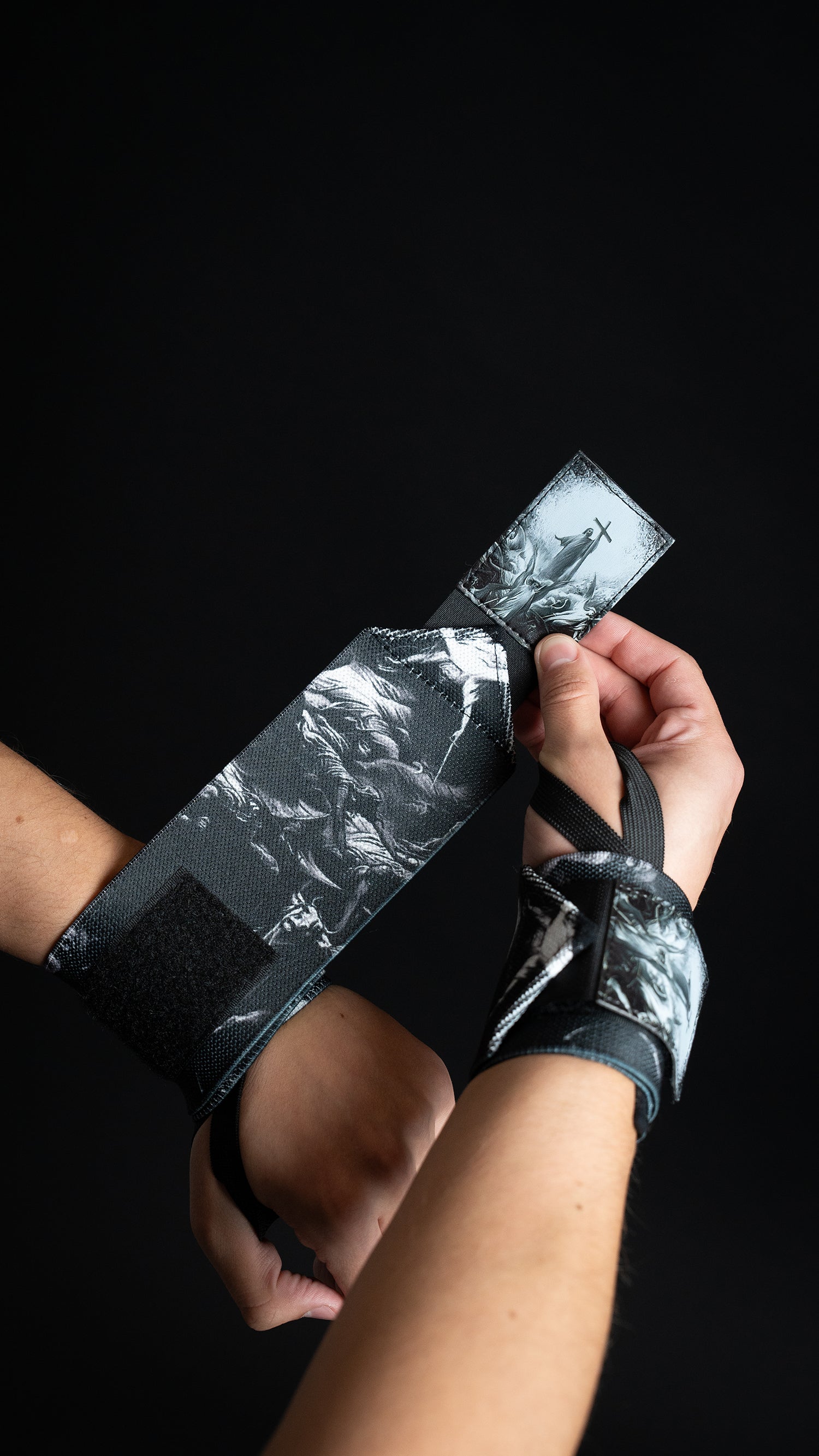 Saint Kaizen Light In The Darkness Wrist Wraps. Christian gym wear accessory featuring bold spiritual print and heavy-duty Velcro for stability.